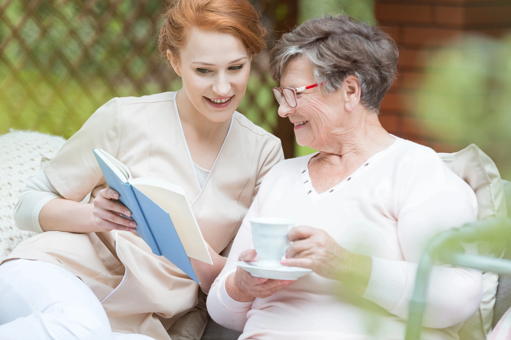 caregiver reading with an elder woman memory care facilities in Chicago